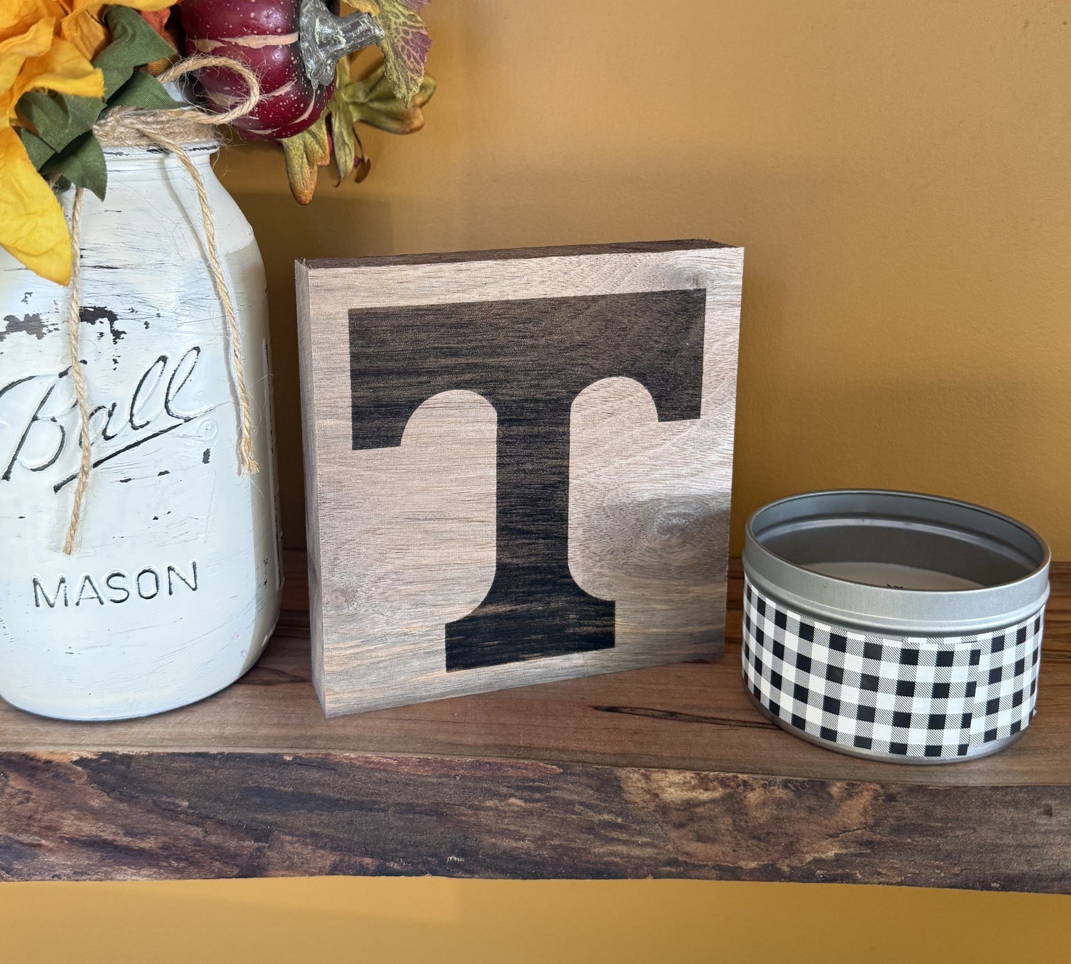 Decorative items including a mason jar, wooden block with University of Tennessee logo', and checkered container on a wooden surface.