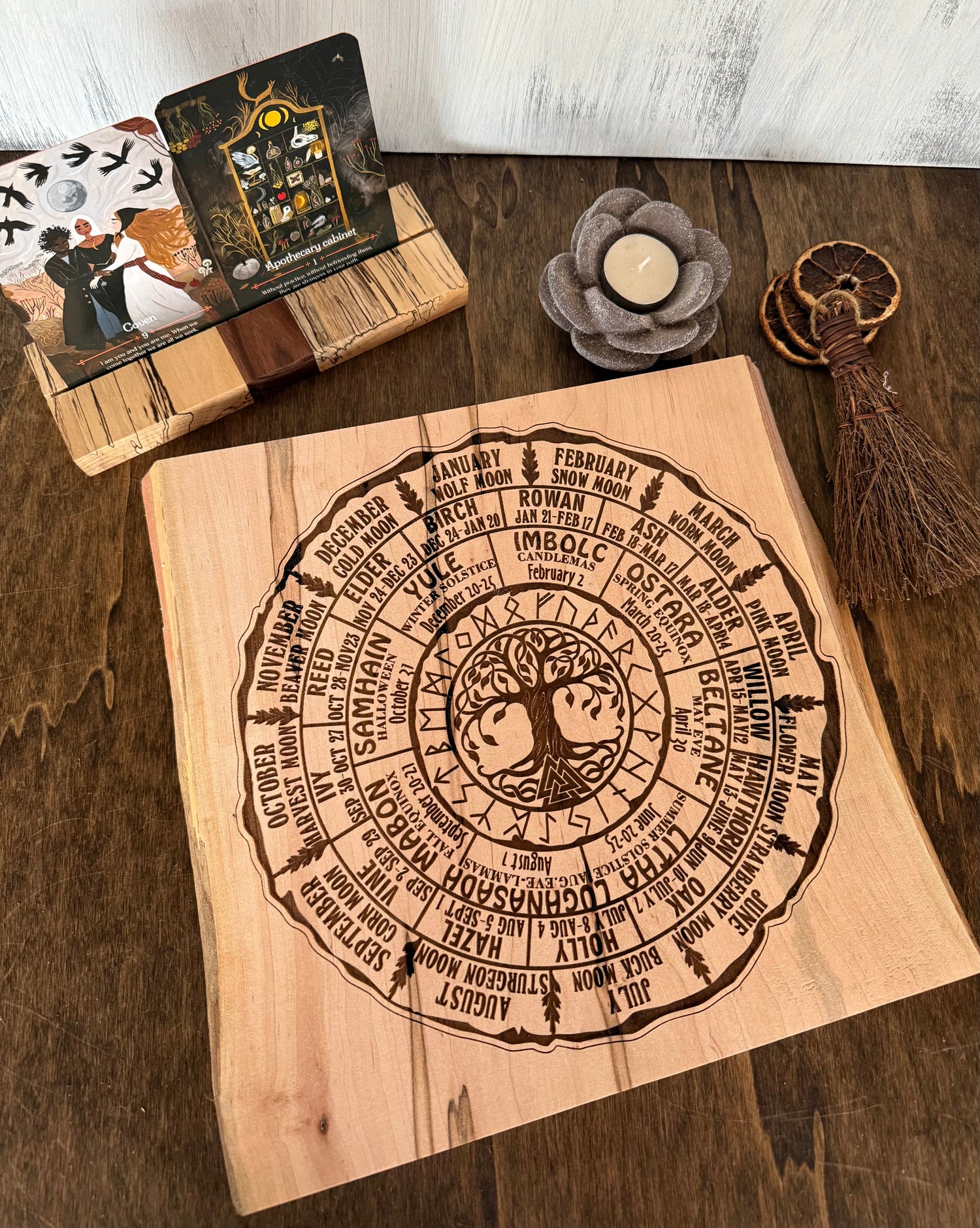 Wooden sign with engraved Pagan Wheel of the Year next to wooden Tarot card holder