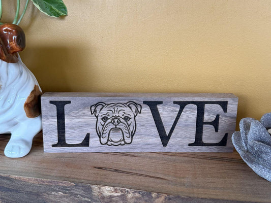 Wooden sign with 'LOVE' and a bulldog illustration on a wooden surface.