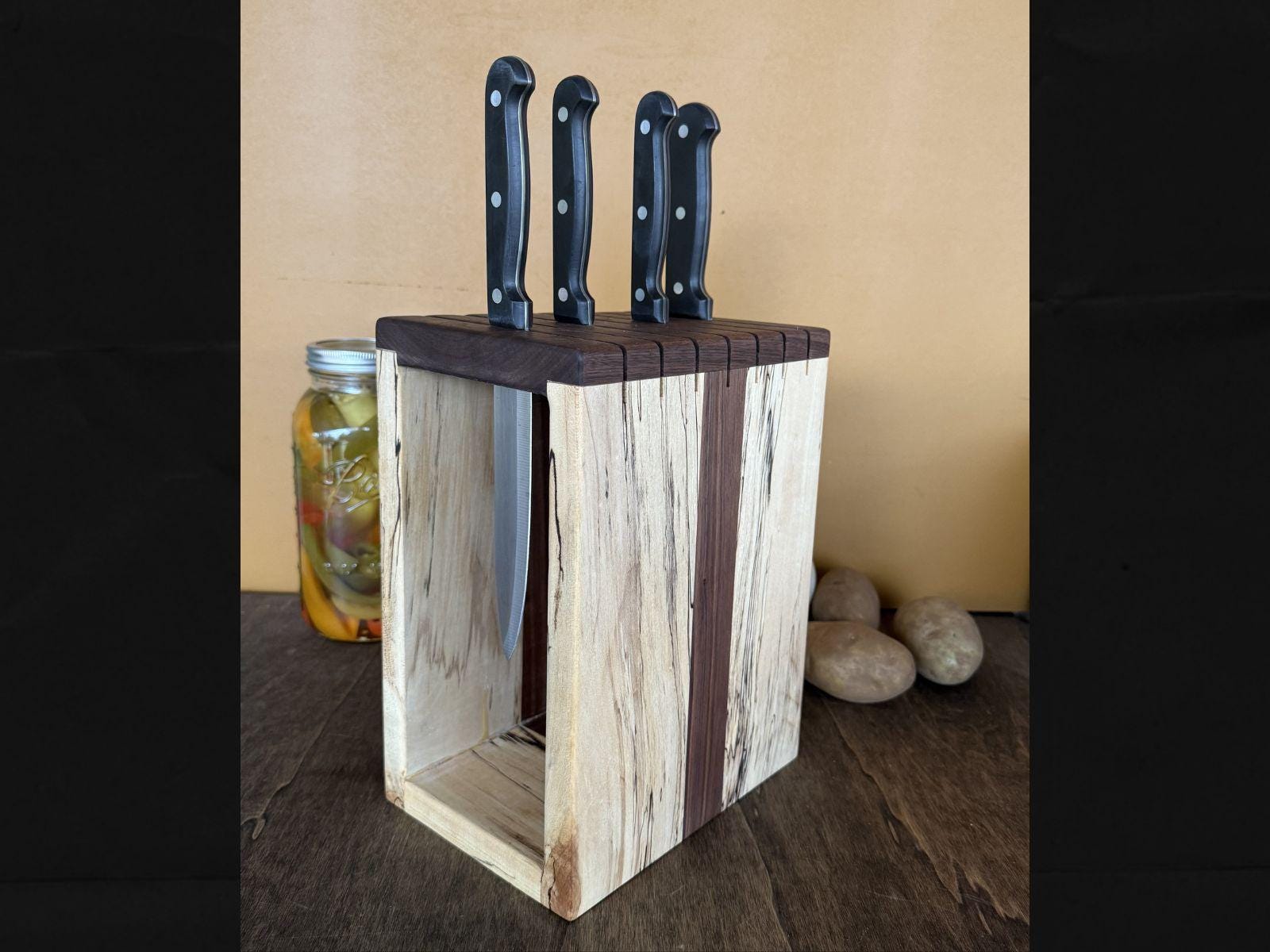 Wooden knife block with four knives on a wooden surface.