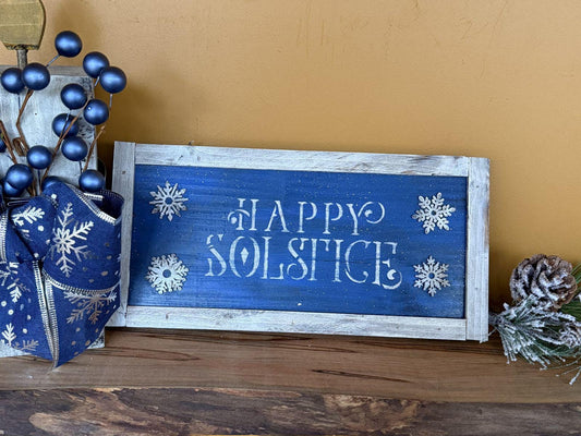 Decorative sign with 'Happy Solstice' text on a wooden surface with festive decorations.