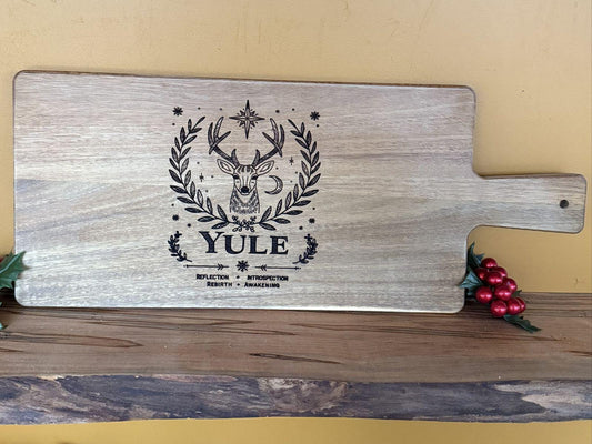 Wooden cutting board with 'Yule' design on a wooden surface