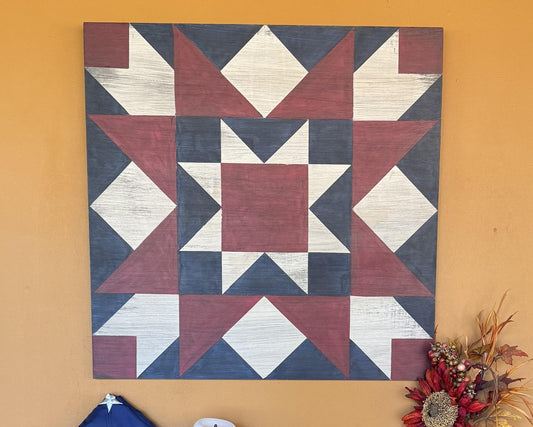 Red, white and blue barn quilt with geometric star pattern on a yellow wall