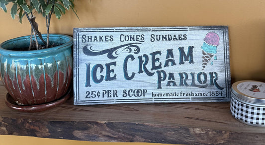 Wooden sign for an ice cream parlor with decorative elements on a wooden surface.