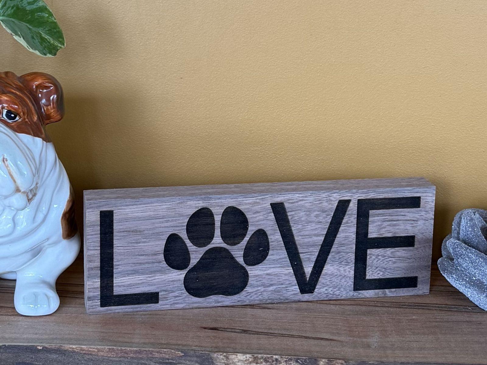 Wooden sign with 'LOVE' and a paw print on a wooden surface.
