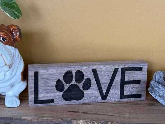Wooden sign with 'LOVE' and a paw print on a wooden surface.
