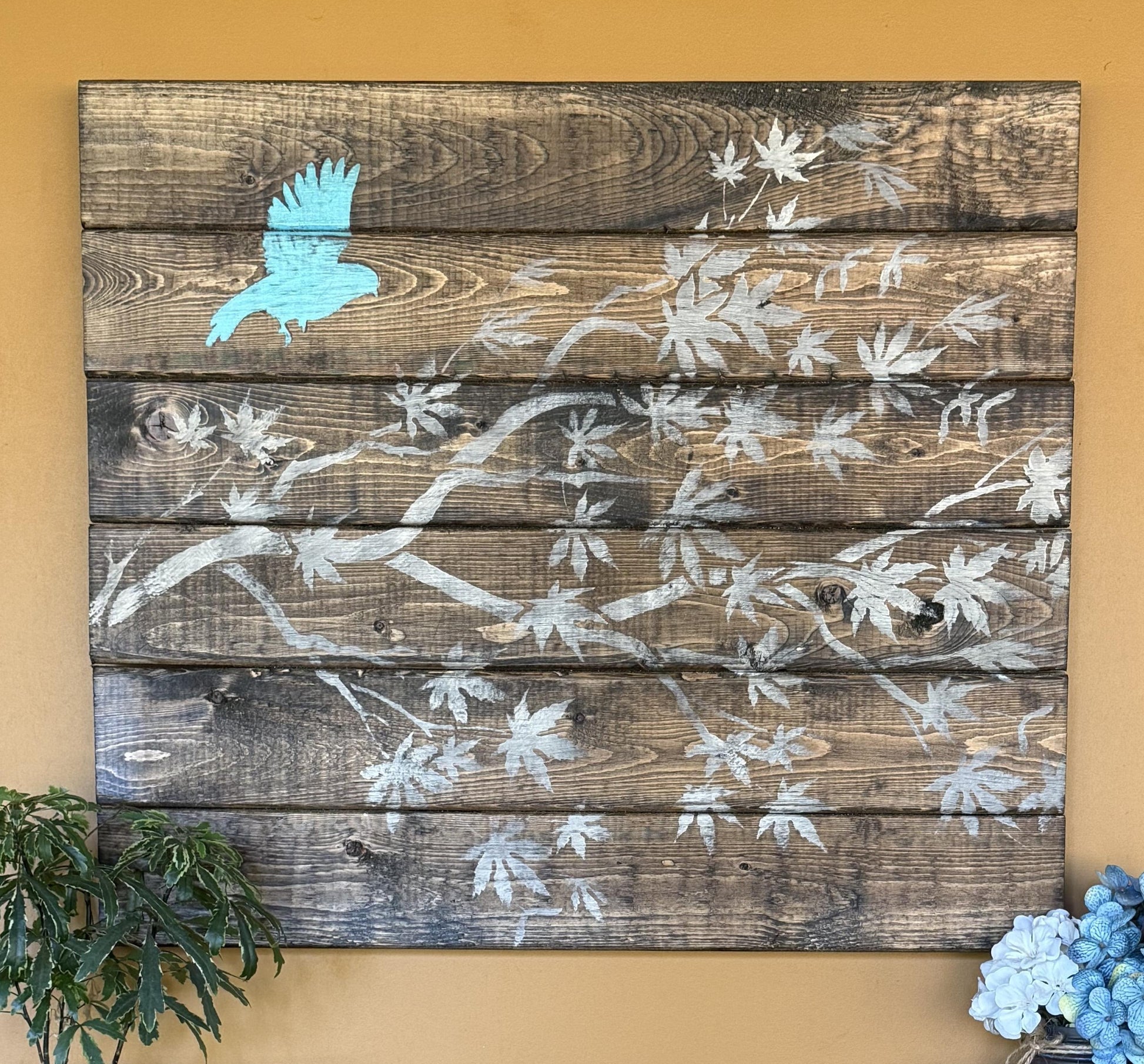 Wooden wall art with floral patterns and a blue bird on a beige background