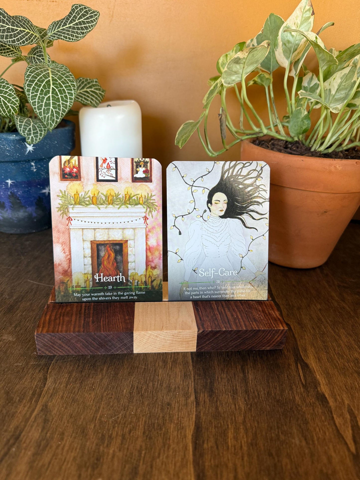 Two oracle cards on a wooden stand with plants in the background