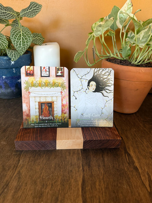 Two oracle cards on a wooden stand with plants in the background