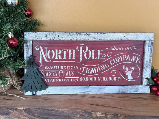 Decorative sign with 'North Pole Trading Company' text, surrounded by Christmas decorations.