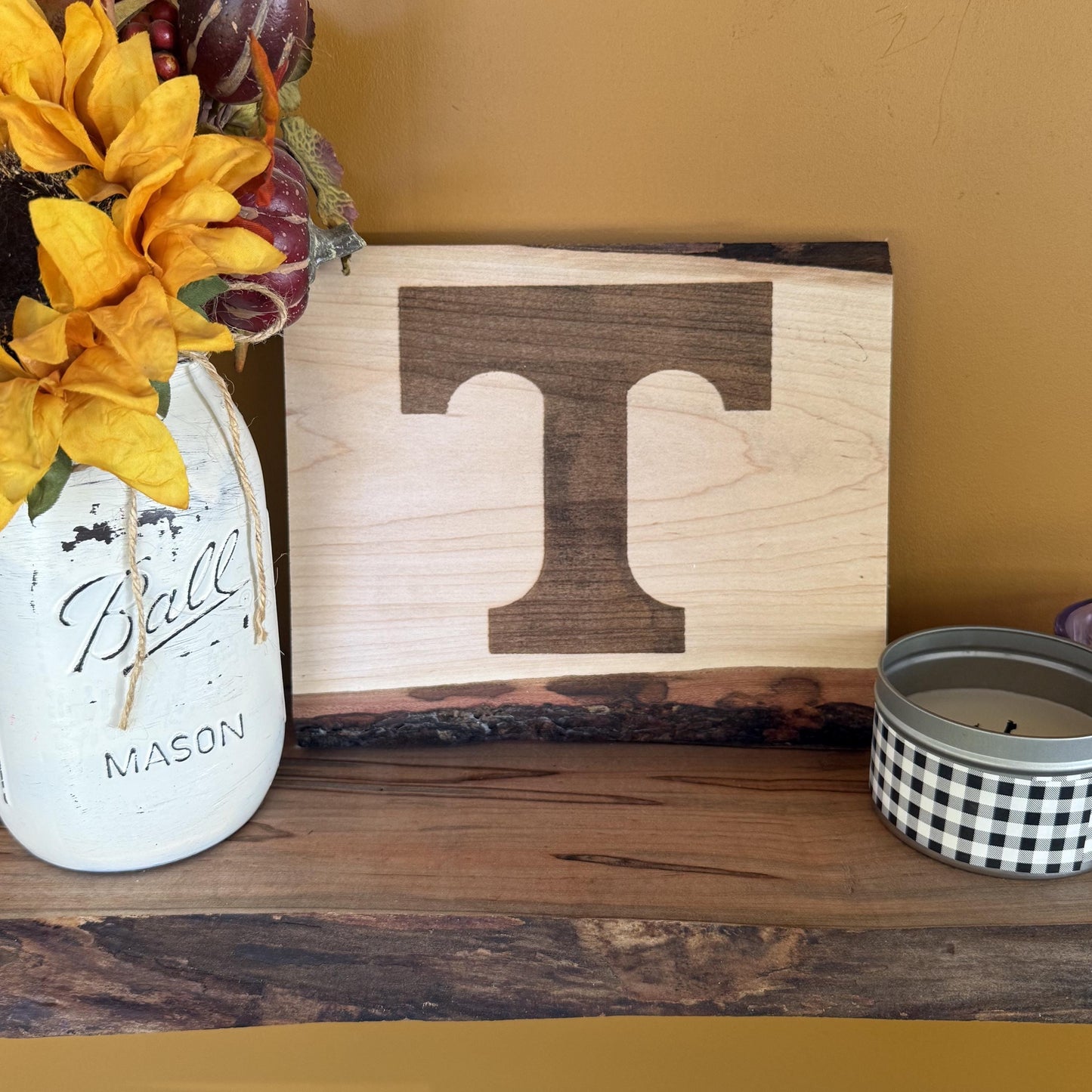 Wooden block with University of Tennessee logo on a wooden shelf with decorative items.