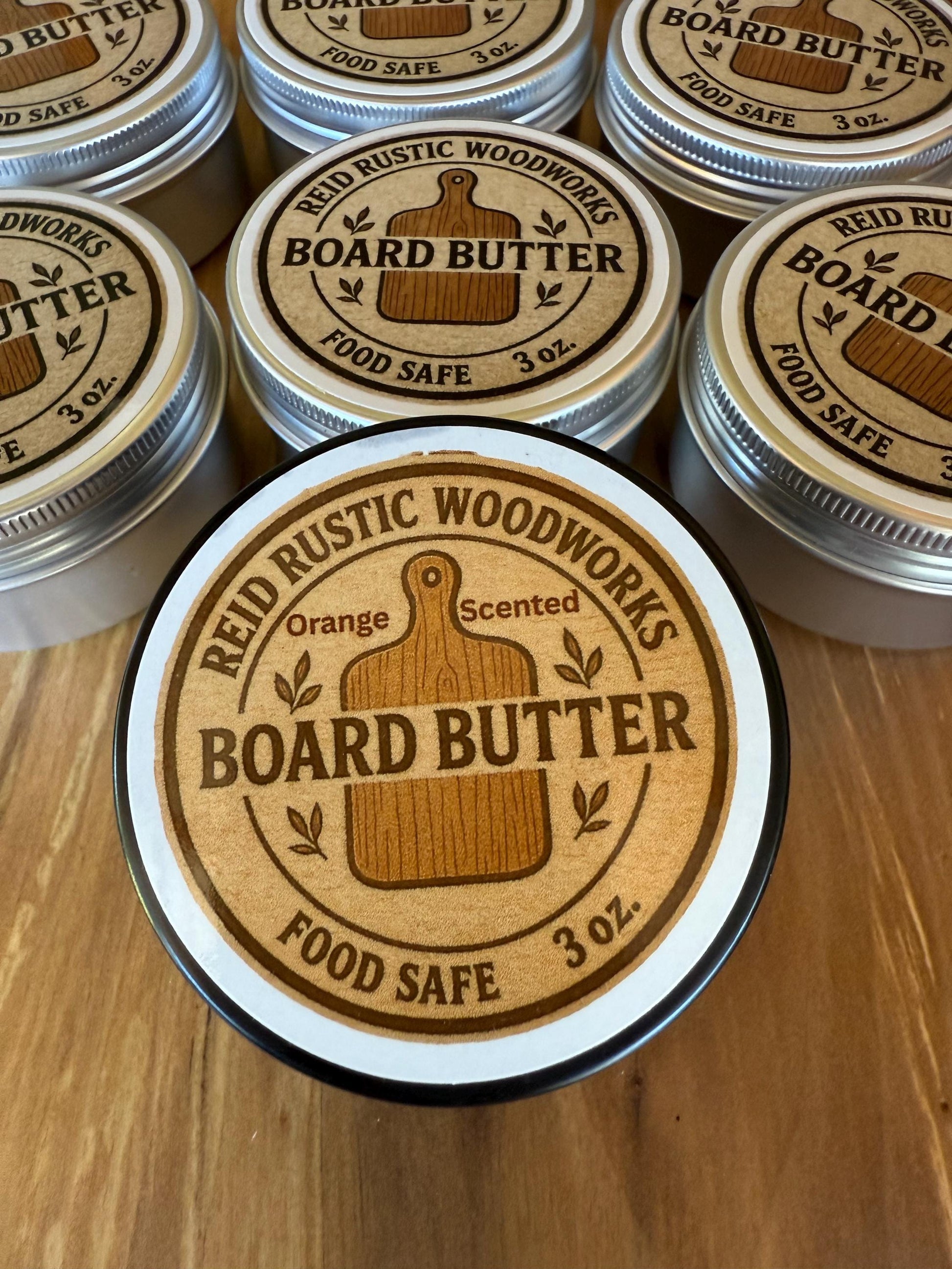 Jars of Reid Rustic Woodworks orange scented Board Butter on a wooden surface