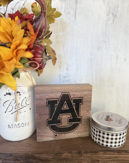 Decorative items including a mason jar, wooden block with Auburn University logo, and small container on a wooden surface.