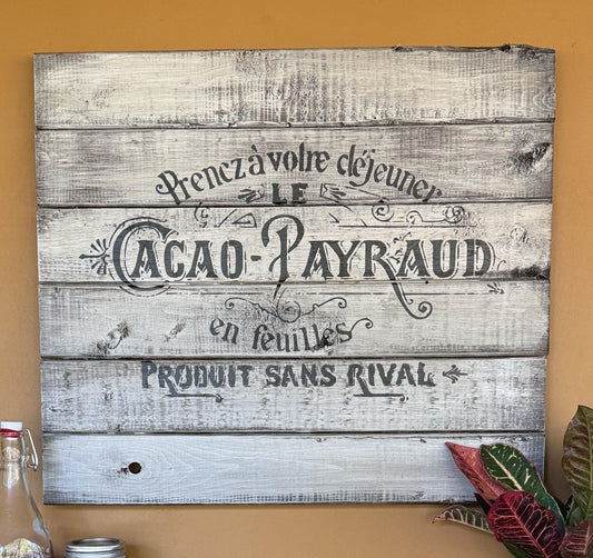 Wooden sign with vintage-style text of a French chocolate ad on a wall
