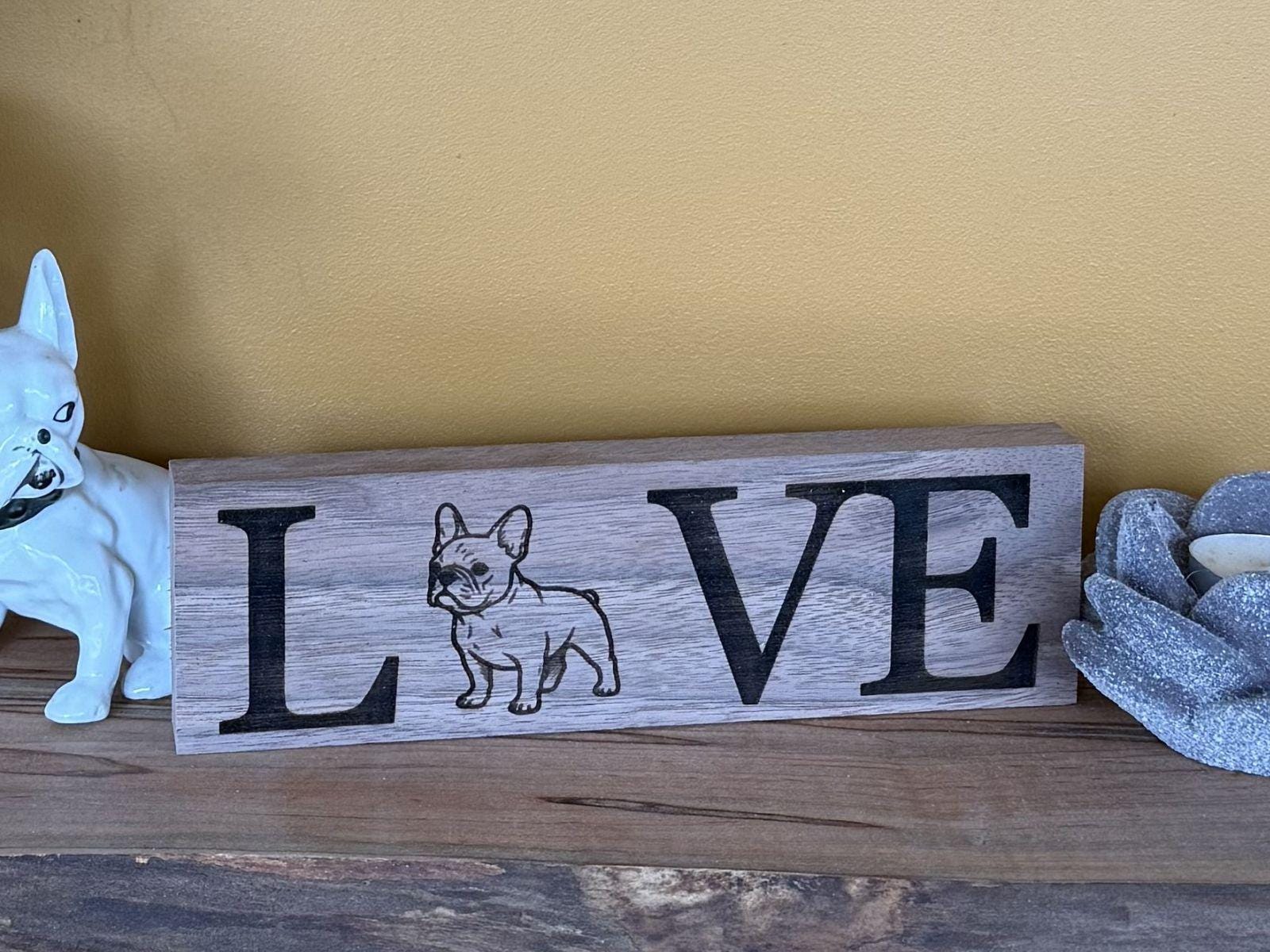 Wooden sign with 'LOVE' and a French bulldog illustration on a wooden surface.