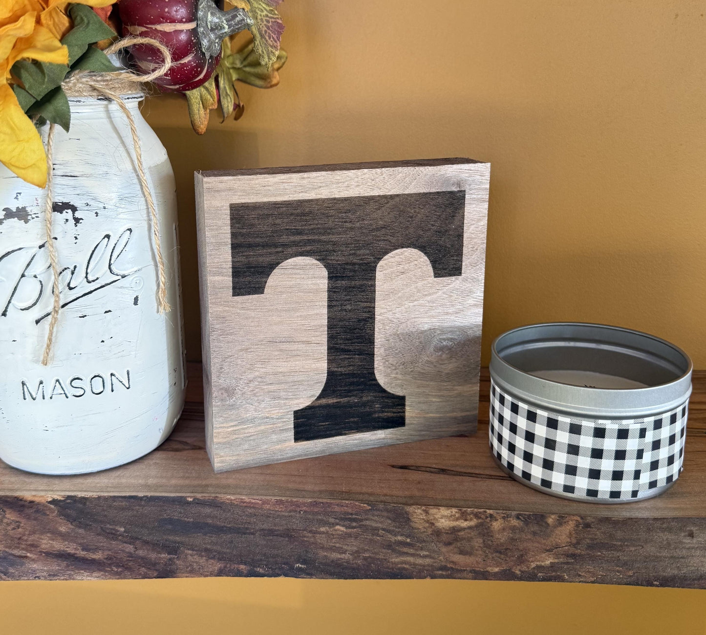 Decorative items including a mason jar, wooden block with University of Tennessee logo', and checkered container on a wooden surface.